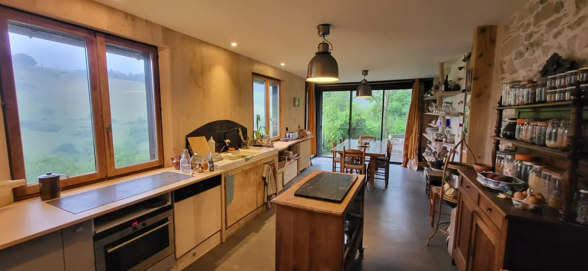 Large wooden kitchen bathed in light, open onto the dining room