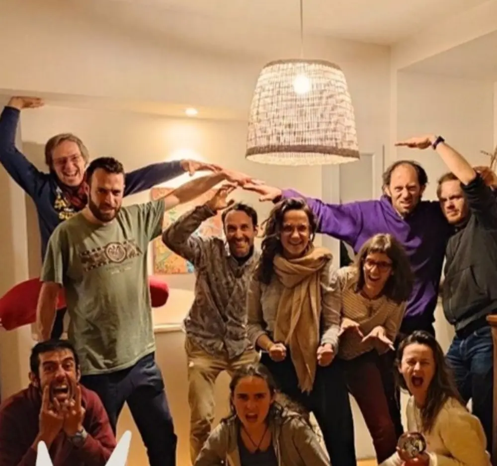 The team and supporters of La Maison Passerelle, gathered and joyful, arms raised like a roof