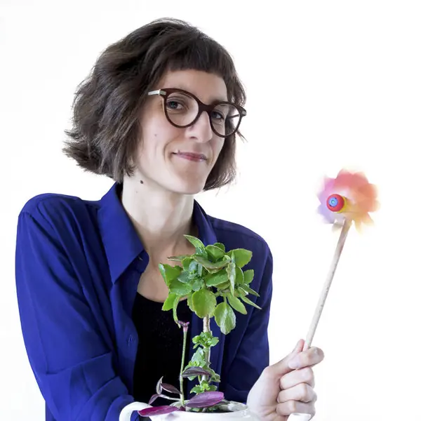 Portrait of Ludivine Thiburs, holding a colourful pinwheel and a plant