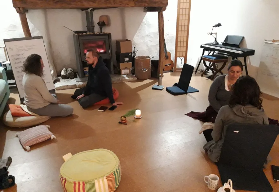 A talking circle around the wood stove, five people sitting on cushions